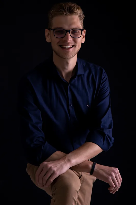 Ricardo Werlang sorrindo, camisa azul-marinho, fundo preto.