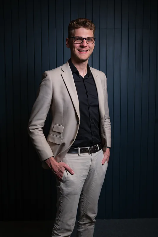 Ricardo Werlang de blazer bege, fundo azul-marinho.
