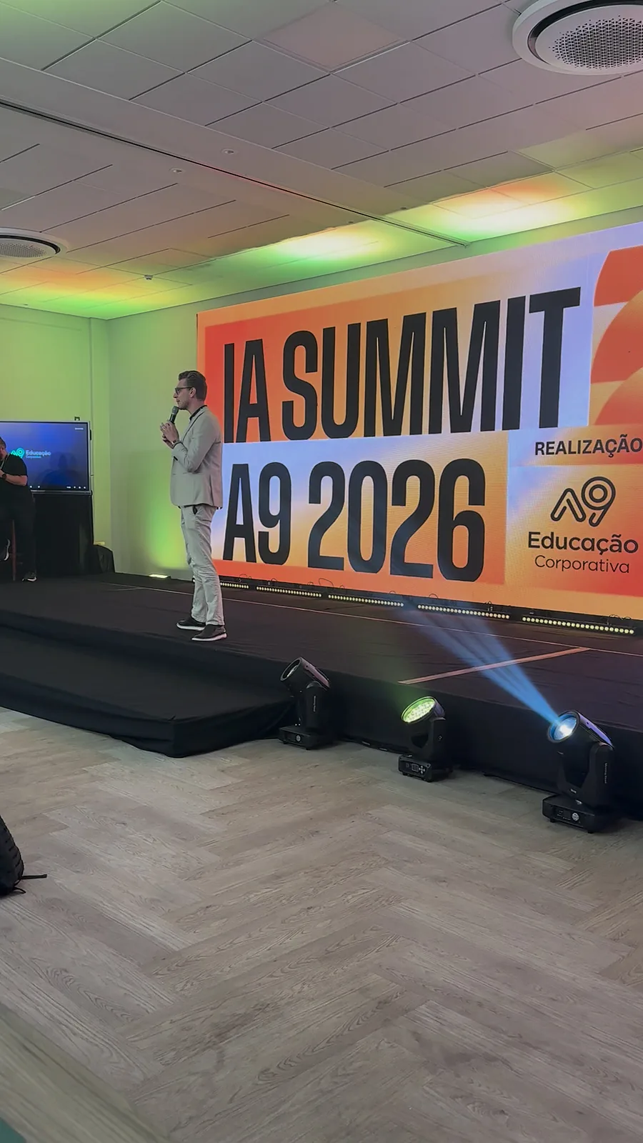 Ricardo Werlang no palco do IA Summit A9 2026, diante do painel do evento.
